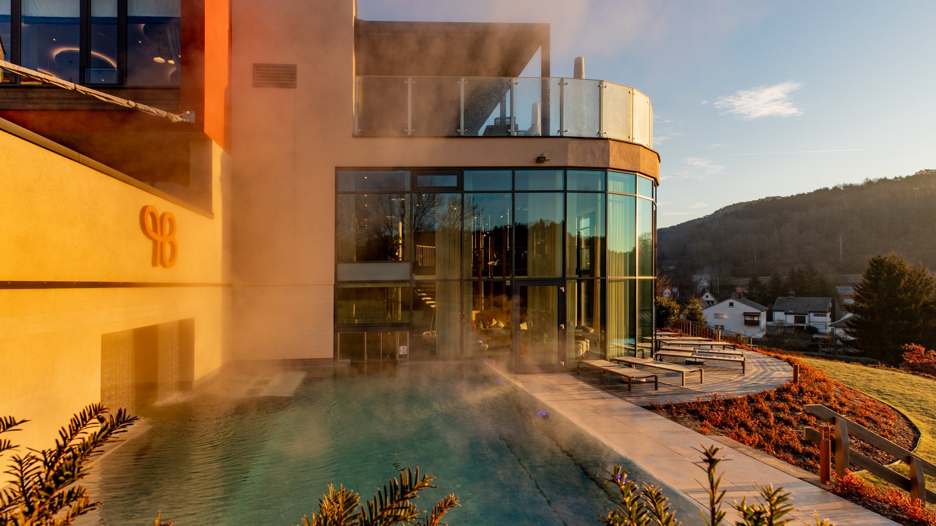 Moderner Wellnessbereich mit Außenpool und Liegestühlen bei Sonnenuntergang