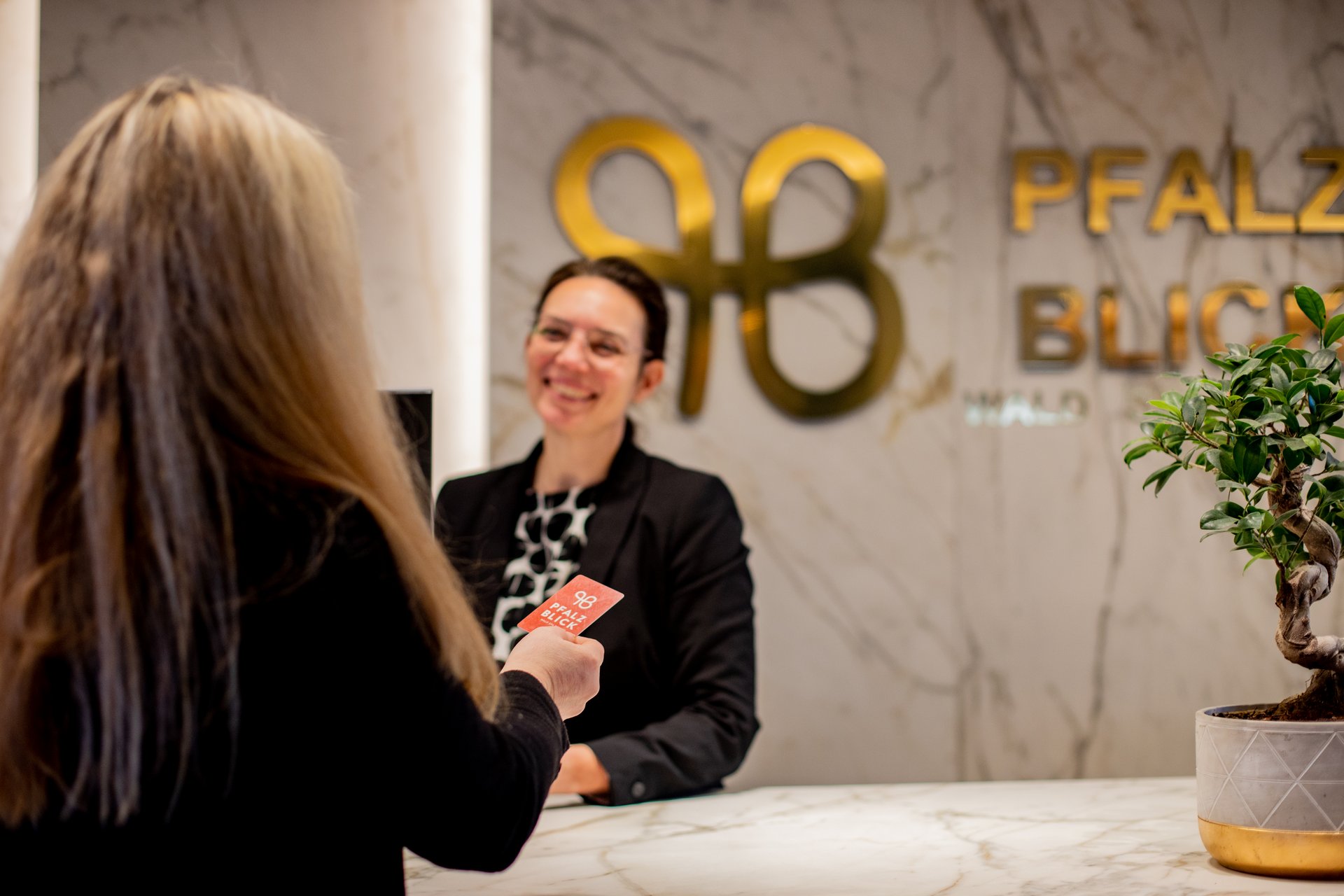 Frau übergibt Karte an Empfangsdame im Pfalzblick Hotel