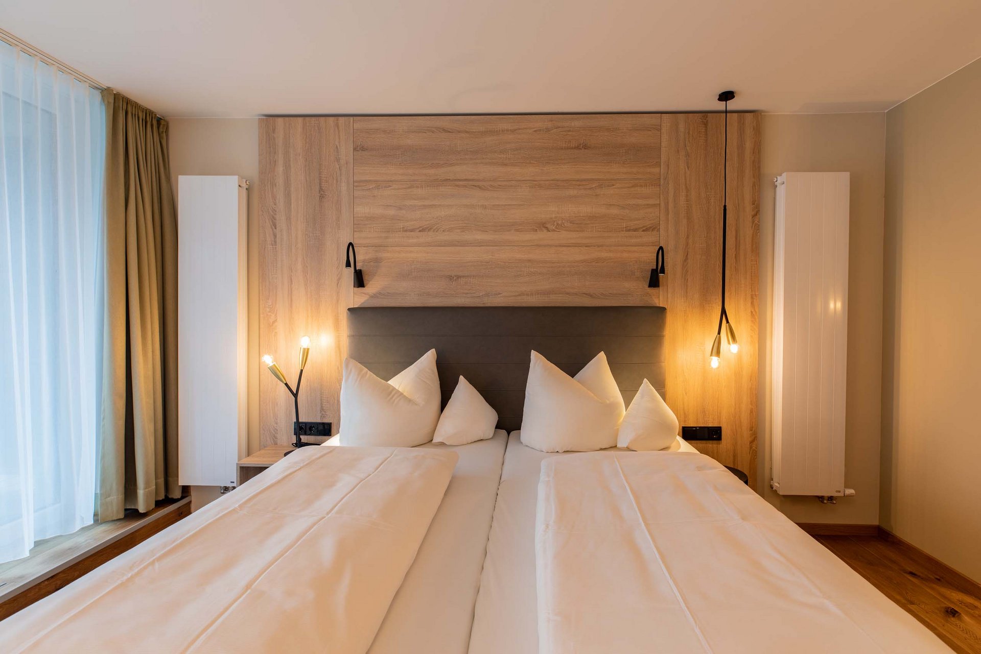 Modern eingerichtetes Doppelbett mit Holzpaneelen und warmem Licht