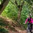 Frau fährt Mountainbike auf Waldweg bei sonnigem Wetter