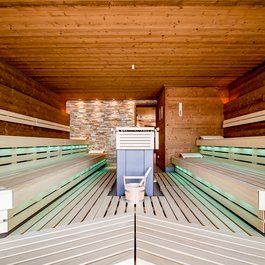 Moderne finnische Sauna mit Holzbänken und Eimer mit Schöpfkelle