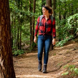 Frau in rotem Hemd wandert auf Waldweg
