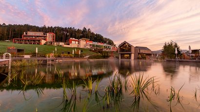 Hôtel au bord d'un lac avec paysage vert au coucher du soleil