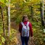 Frau mit Rucksack wandert auf Waldweg im Herbst