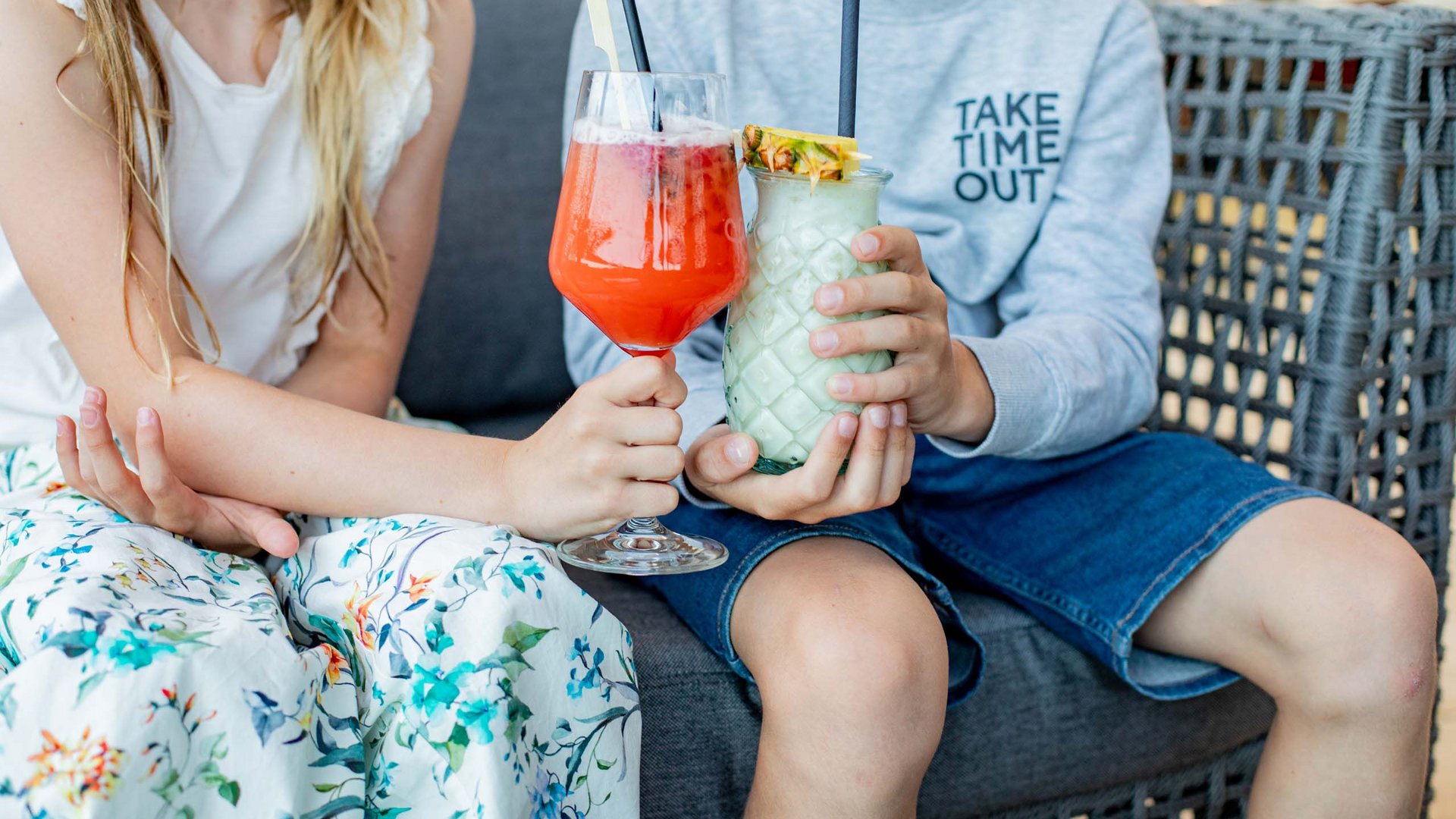 Kinder sitzen mit bunten Getränken auf einem Sofa