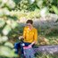 Femme en pull jaune sort une bouteille de vin d'un sac à dos en forêt