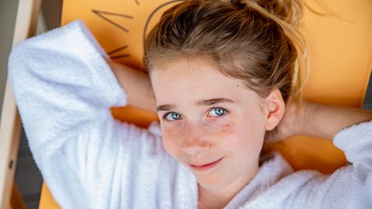 Mädchen mit blauen Augen in weißem Bademantel entspannt liegend