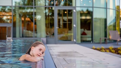 Mädchen lehnt nachdenklich am Rand eines modernen Pools