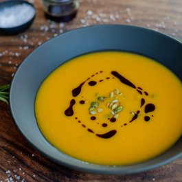 Kürbissuppe mit Kürbiskernen und Balsamico-Glasur in schwarzer Schüssel