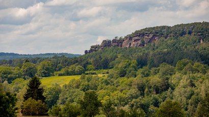 Grüne bewaldete Hügel und Felsen unter bewölktem Himmel