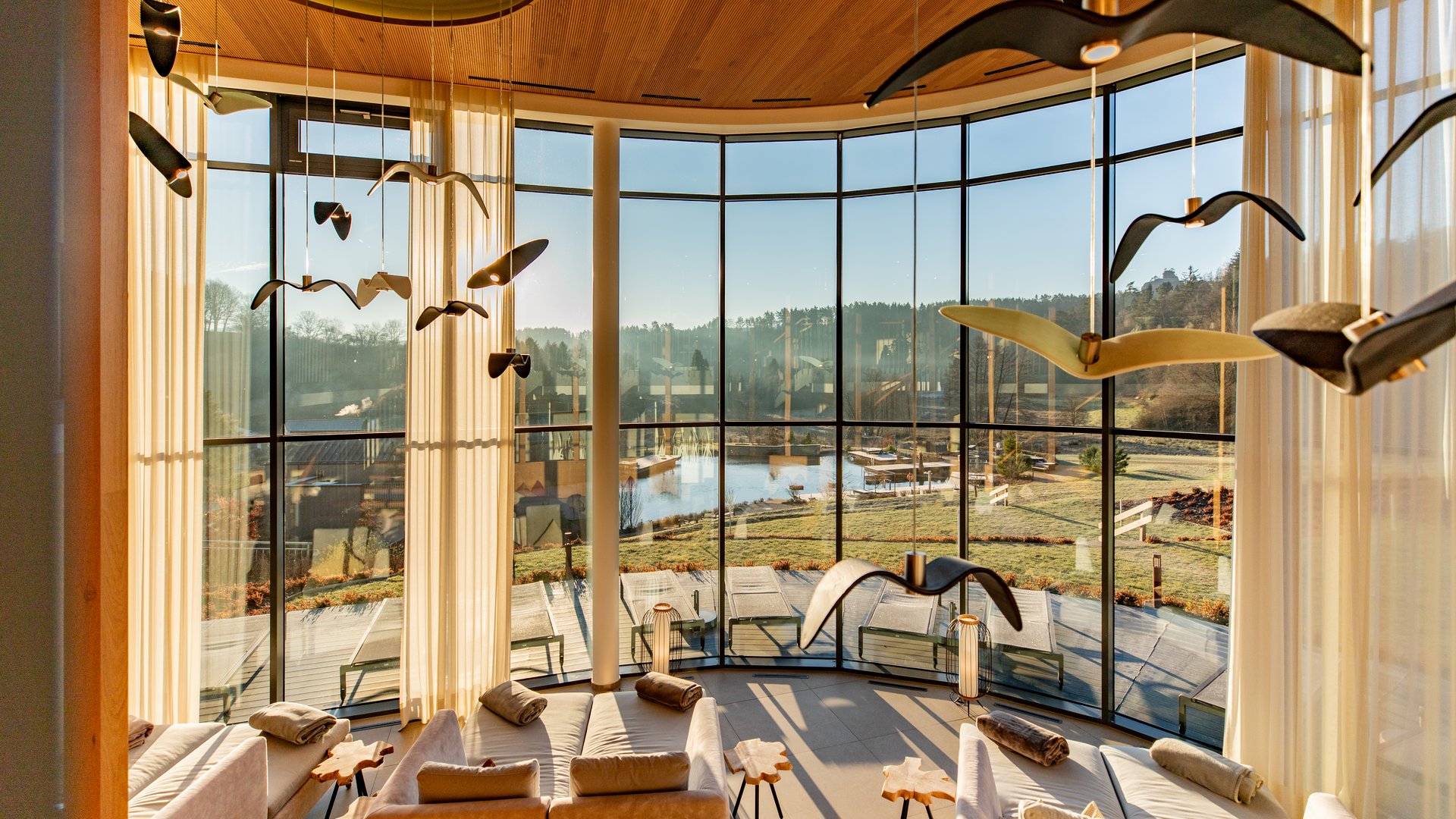 Gemütlicher Aufenthaltsraum mit Panoramafenstern und Blick auf Garten und See