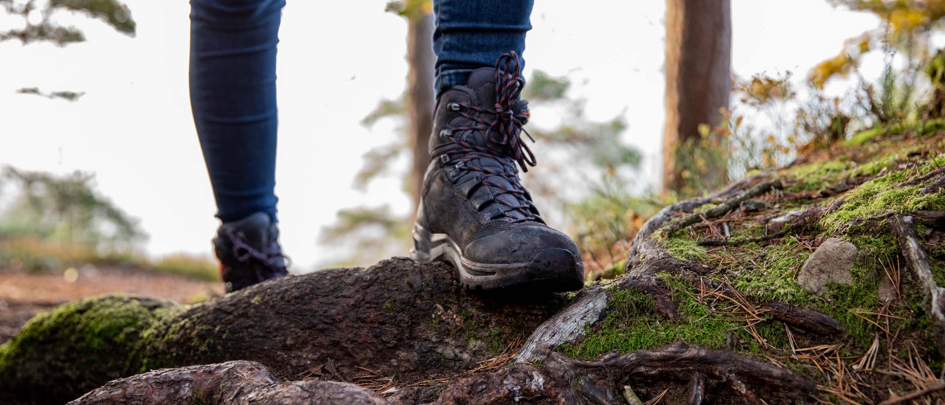 Wanderstiefel auf moosbewachsenen Baumstämmen im Wald