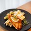 Schnitzel mit weißem Spargel, Kartoffeln und Sauce auf schwarzem Teller