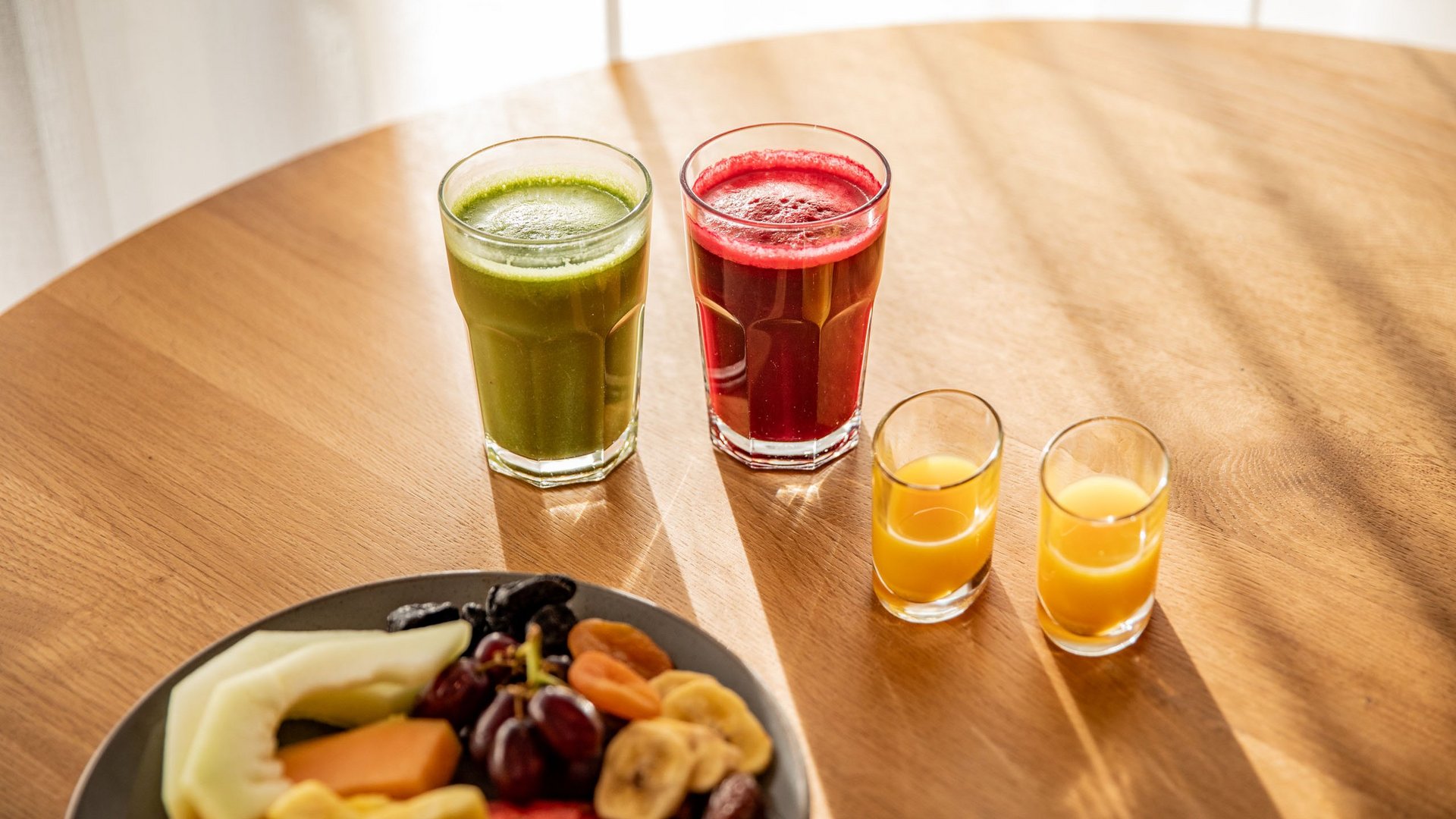 Frühstück mit frischen Säften und Früchten auf einem Holztisch
